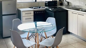 A modern kitchen with a dining table, chairs, a stove, microwave, and a refrigerator. - Charming 3-bedroom House Rental in Centurion, South Africa (Centurion)