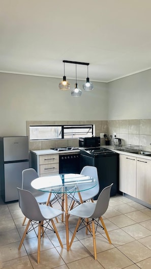 A modern kitchen with a dining table, chairs, a stove, microwave, and a refrigerator.