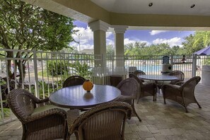 A covered outdoor seating area with wicker furniture and a view of a swimming pool. - Charming 2-bedroom apartment with AC in Kissimmee (Kissimmee)