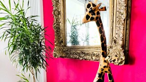 A room with a bright pink wall, a large ornate mirror, and a tall giraffe sculpture. - Luxury Lakeview Home with Pool • Nature Retreat for Groups in charming Granada (Granada)