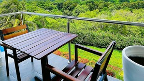 A terrace with a table and chairs, a railing, and a view of a lush landscape. - Luxury Lakeview Home with Pool • Nature Retreat for Groups in charming Granada (Granada)