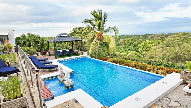A swimming pool with lounge chairs, a gazebo, and a view of the surrounding landscape. - Luxury Lakeview Home with Pool • Nature Retreat for Groups in charming Granada (Granada)