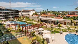 A hotel with a pool area, outdoor seating, and a view of surrounding buildings. - FLAT BEACH CLASS SUMMER - PORTO (Ipojuca)