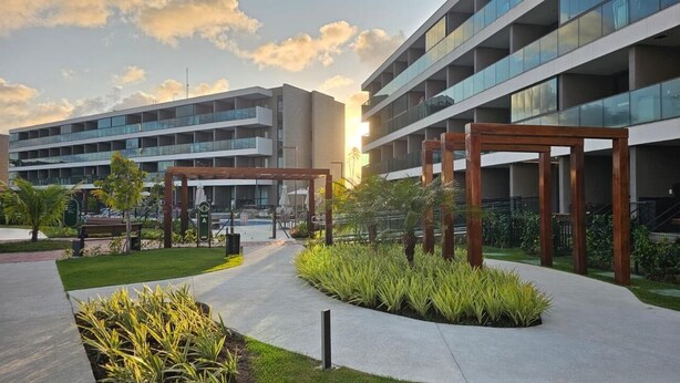 A modern building with multiple floors, outdoor seating, and greenery. - FLAT BEACH CLASS SUMMER - PORTO (Ipojuca)