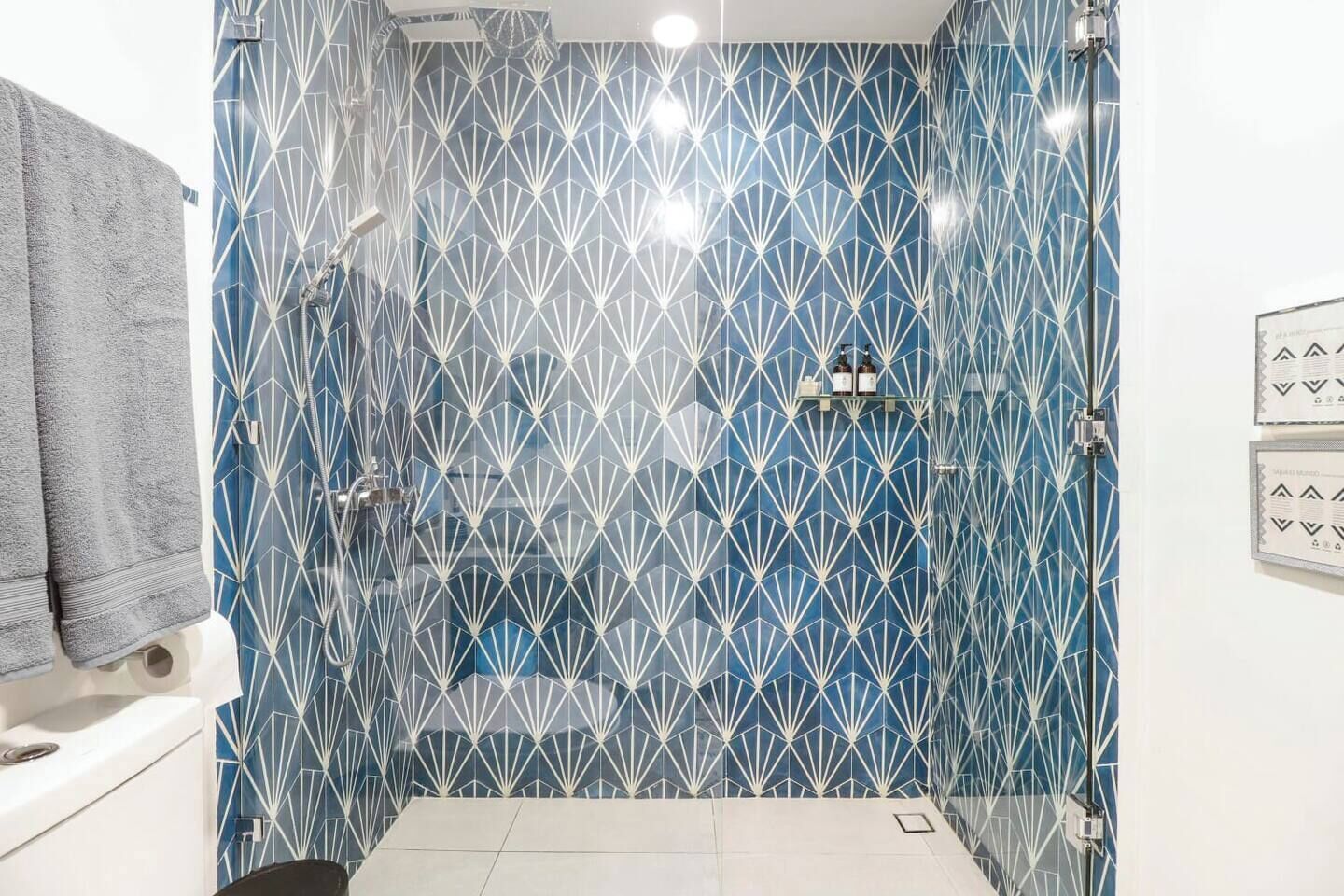 A bathroom with a geometric tile pattern on the walls, a shower, and a toilet.