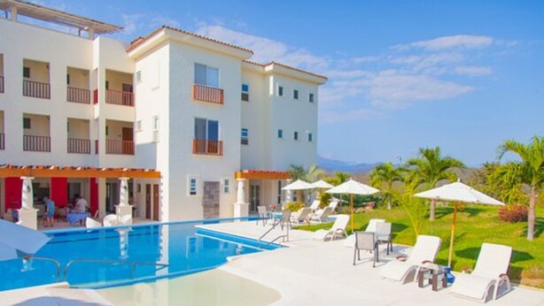 Un hotel con piscina, poltrone a sdraio e vista sulle montagne.