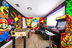 A room with a foosball table, a sofa, and a gaming console.