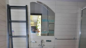 Un bagno con un lavandino bianco, uno specchio, una doccia e un tappeto a righe.