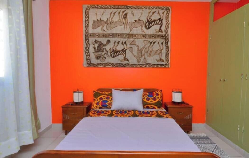 Une chambre à coucher comprenant un lit, deux tables de chevet, une décoration murale et une armoire.