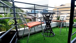 Un balcone con un tavolo rotondo, due sedie e pavimento in erba sintetica.