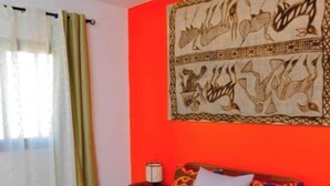 Una camera da letto con un letto di legno, un tappeto decorato, una parete di colore rosso e un arazzo.
