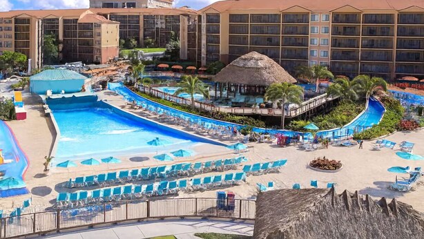 A resort with a large swimming pool, multiple lounge areas, and a thatched-roof structure. - Orlando Studio Villa Near Disney - Westgate Lakes (Orlando)