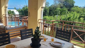 Une terrasse avec une piscine, des sièges d’extérieur et une table dressée pour deux personnes.