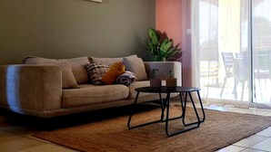 Un salon avec un canapé, une petite table, une plante en pot et une porte-fenêtre coulissante.
