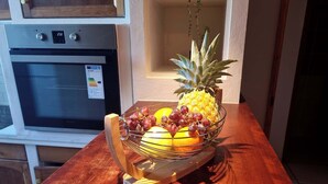 Un plan de travail de cuisine avec un panier de fruits contenant des raisins, des citrons et un ananas.