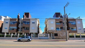 Um edifício residencial com vários andares, varandas e portão fechado.