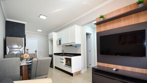 Uma cozinha moderna com armários brancos, bancada preta e forno embutido.