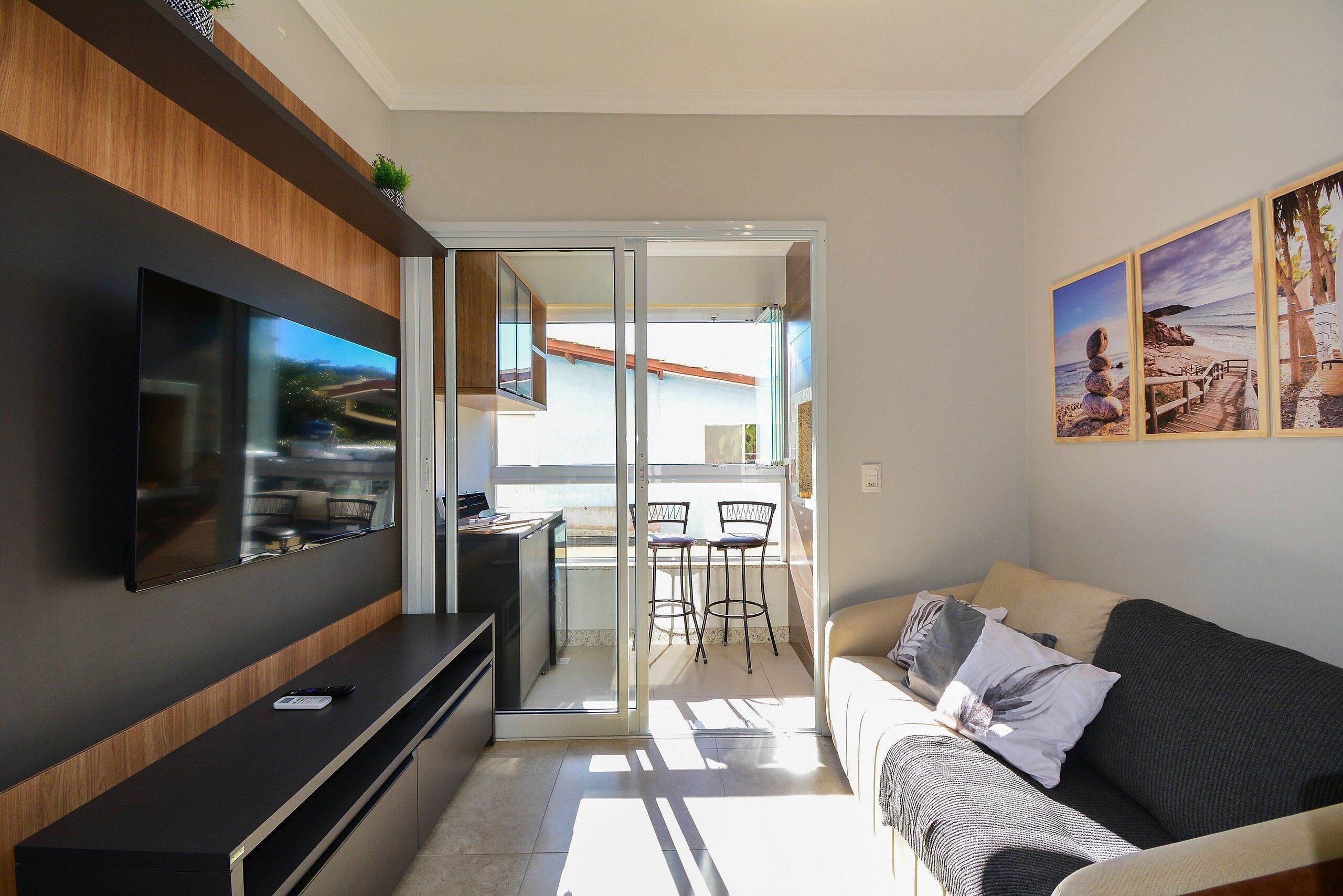 A modern living room with a flat-screen TV, a sofa, and a balcony with a dining area.
