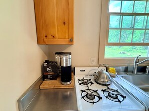 Eine Küche mit Gasherd, Wasserkocher, Kaffeemaschine und Kaffeekartons von Peet's Coffee.