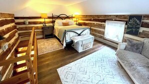 Una stanza accogliente con un letto, un comodino, una lampada e un divano.