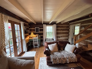 Ein rustikales Holzhaus-Interieur mit Ledersofa, einem Holztisch und einer Treppe.
