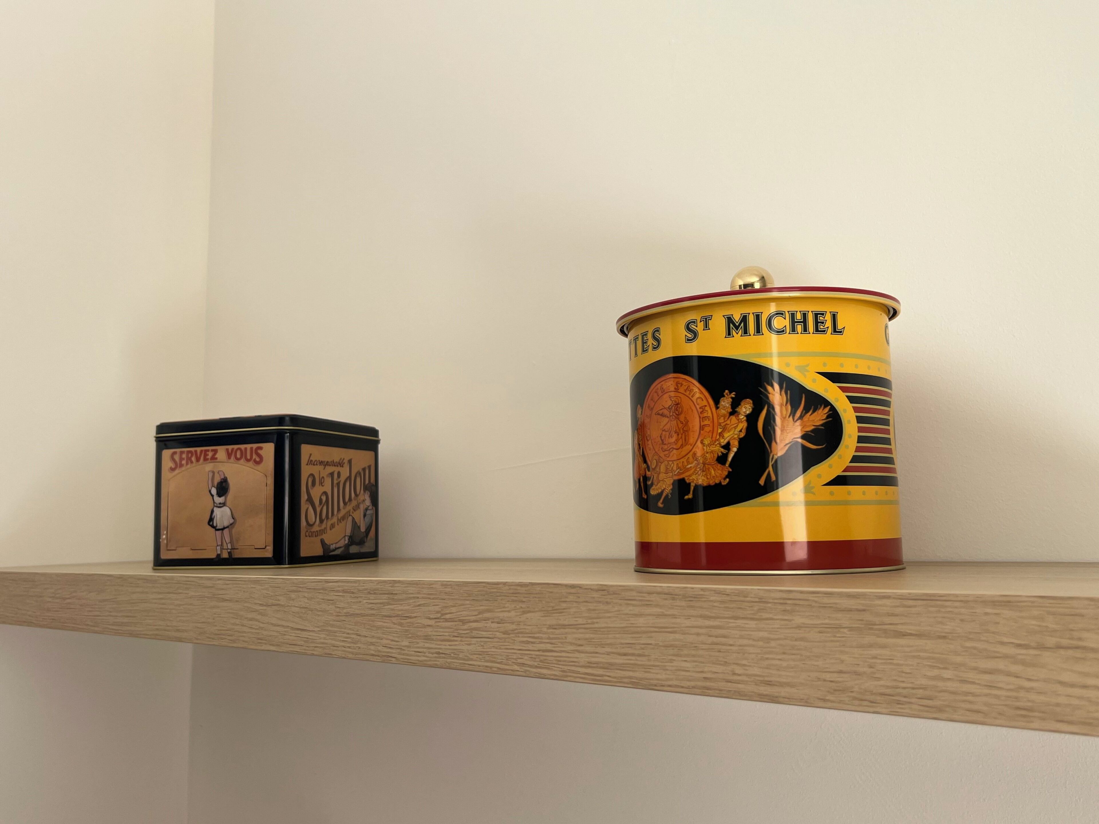 Two vintage-style tin containers on a wooden shelf.