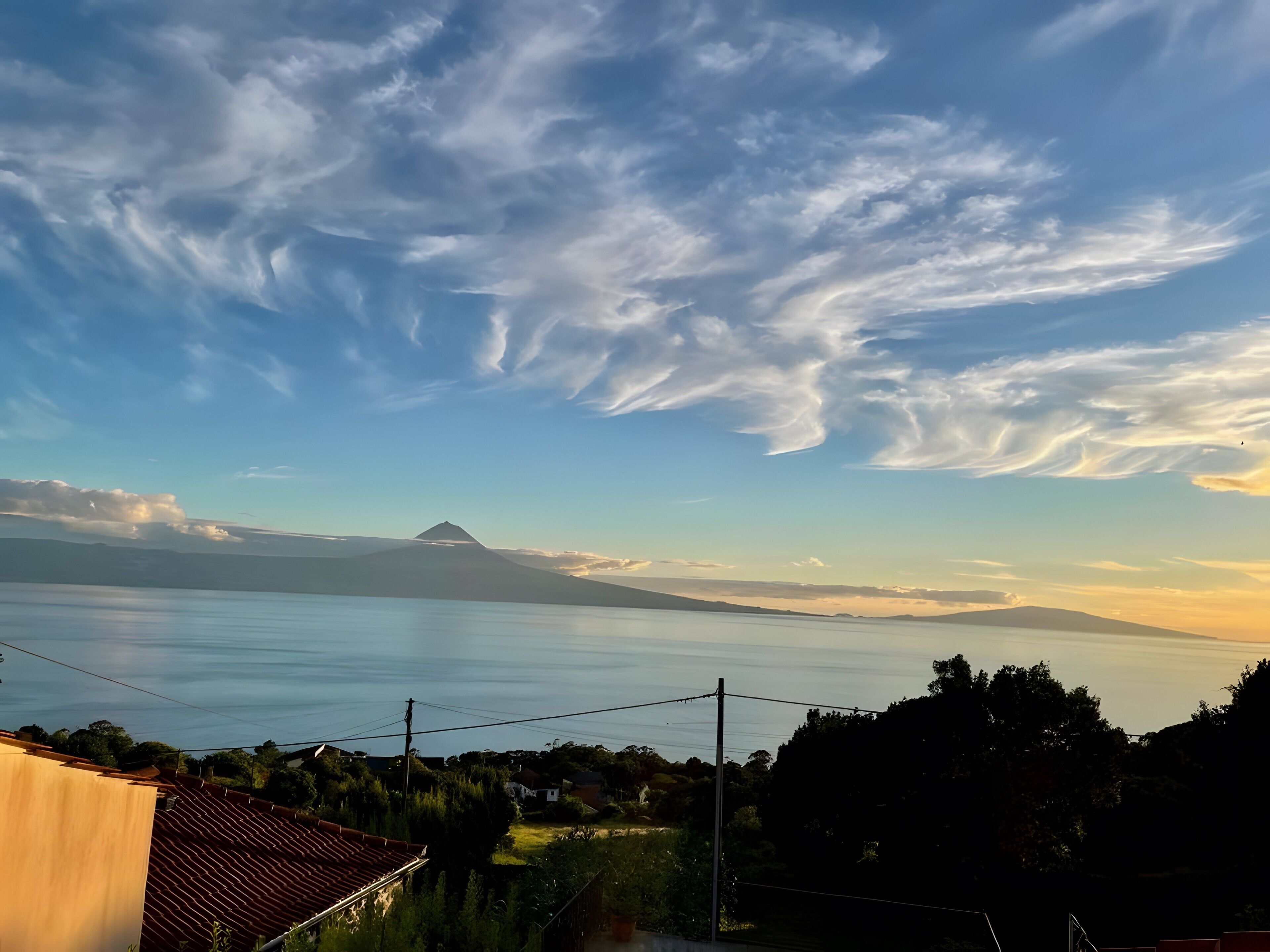 Un paysage côtier avec une montagne à l’horizon, des lignes électriques et des immeubles d’habitation.