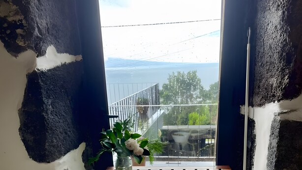 A dining table with two plates, two wine glasses, and a vase with a plant. - Casa da Petra – Our Casa is your Casa (Urzelina)