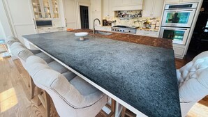 Een moderne keuken met een groot keukeneiland, inbouwmeubels en roestvrijstalen apparatuur.