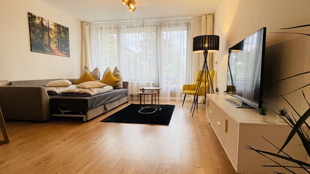Una sala moderna con un sofá, un televisor, una lámpara y un cuadro en la pared.