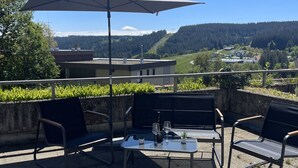 Un patio al aire libre con una mesa, sillas y una sombrilla.