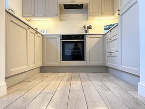 A kitchen with a built-in oven, white cabinetry, and a marble countertop. - DALE VIEW, Youlgreave, bright and cozy cottage in the heart of the Peak District (Youlgreave)