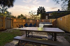 Een achtertuin met een houten omheining, een jacuzzi en een picknicktafel.