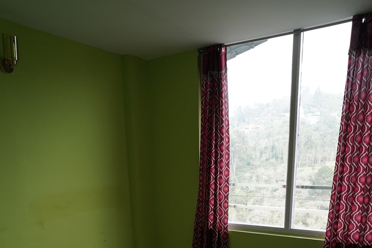 Una habitación con cama, ventana con cortinas y suelo estampado.