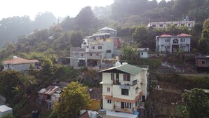 Zona residencial con edificios de varios pisos, algunos con balcones, rodeada de vegetación y colinas.