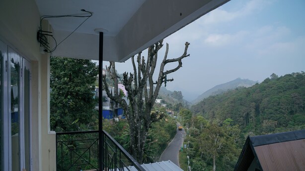 Un balcón con vista a un paisaje montañoso, una silla y una barandilla.