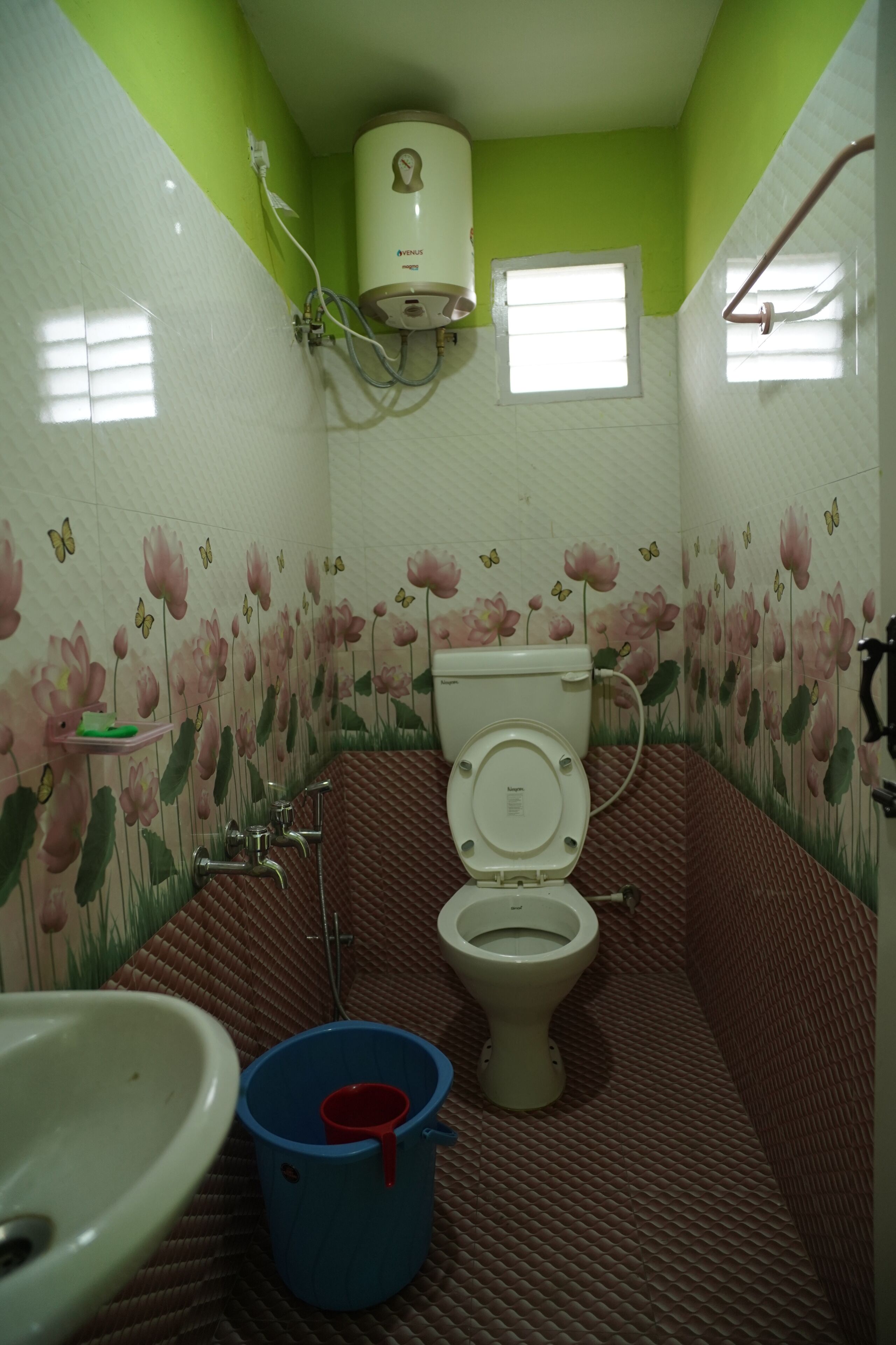 A bathroom with a toilet, a sink, a blue bucket, and a water heater.
