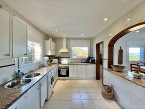 A modern kitchen with white cabinets, a built-in washing machine, and a view of the outdoors. - 4-bedroom house with private pool in charming Begur.. (Begur)