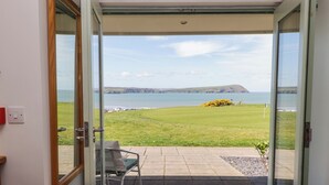 Una habitación con puerta de vidrio corrediza que da a un patio con vista al mar y una zona verde.