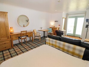 A bedroom with a bed, a desk, a chair, a sofa, a dresser, a mirror, and a window. - Ty Mor (Newport)