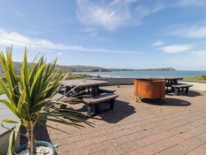 A patio with picnic tables and a barbecue grill overlooking a coastal view. - Ty Mor (Newport)