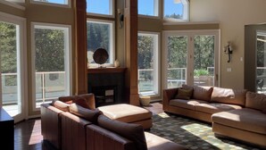 Amplia sala de estar con ventanas grandes, chimenea y un rincón de descanso acogedor.