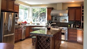 Una cocina moderna con electrodomésticos de acero inoxidable, encimera de granito y un amplio ventanal con vistas al exterior.
