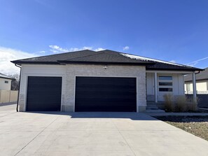 A two-story house with a garage, a covered porch, and a brick facade. - Luxury Oasis in Salt Lake City (West Valley City)