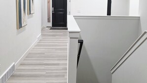 Un interior moderno con suelo de madera, paredes blancas y una escalera.