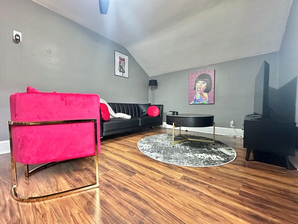 A living room with a black sofa, a red chair, a round coffee table, and a black TV stand.