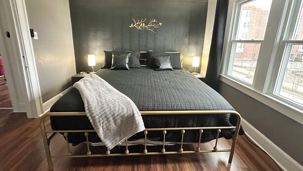 Een slaapkamer met een bed, bedlampjes, een plafondventilator en een raam met uitzicht.