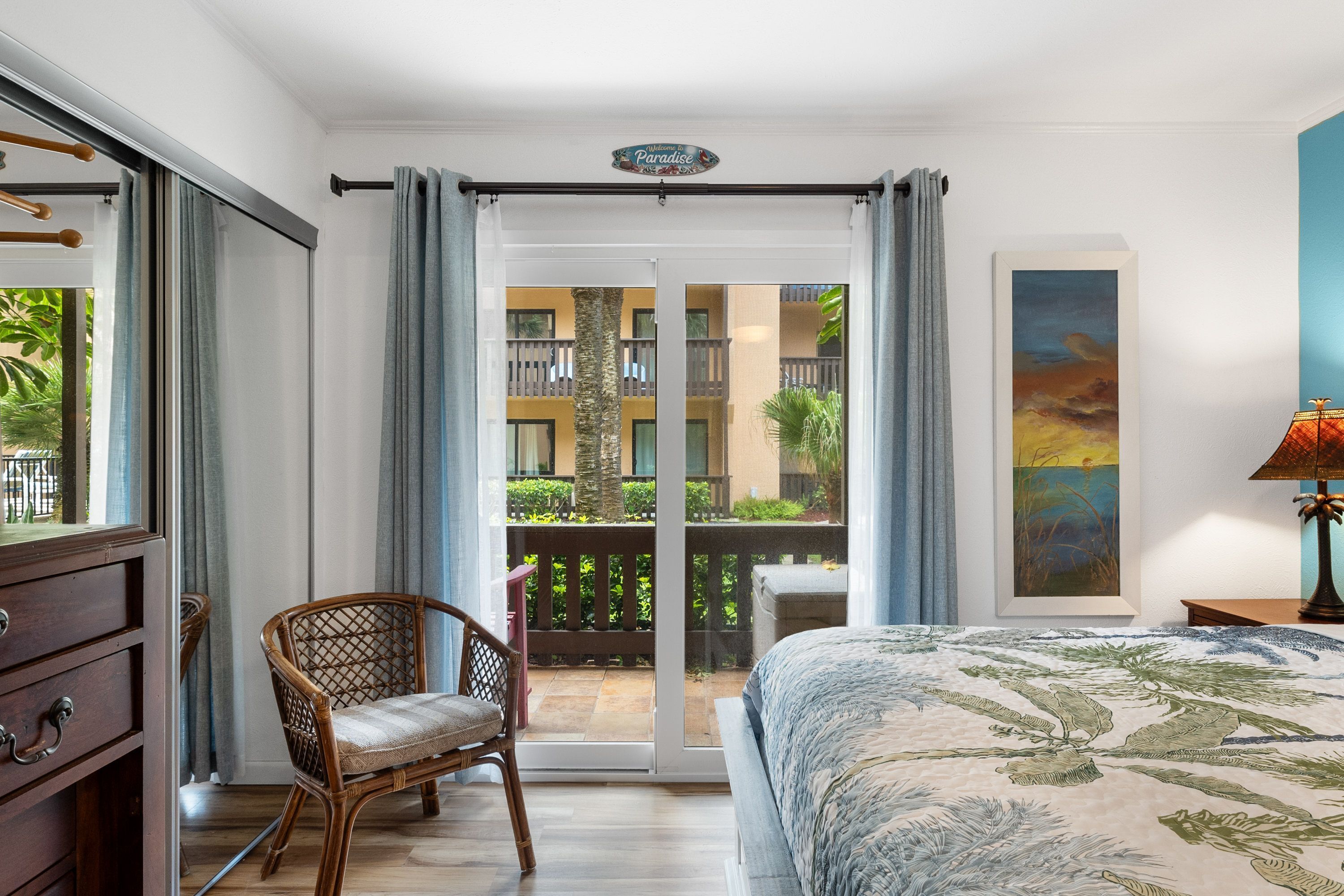 Un dormitorio con cama, una silla, un escritorio y vistas al balcón exterior.