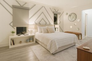 A modern bedroom with a bed, bedside tables, a TV, and decorative mirrors. - The Modern Palm just minutes from Siesta Key! (Sarasota)