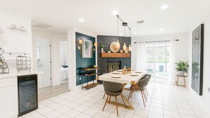 Una cocina moderna con comedor, piso de baldosas blancas y pared de ladrillo negro decorativa.